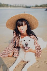 Portrait of young woman sitting at dog at beach