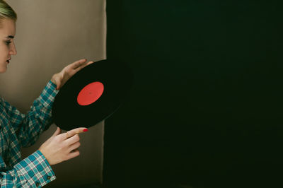Young woman holding vinyl record while standing at home