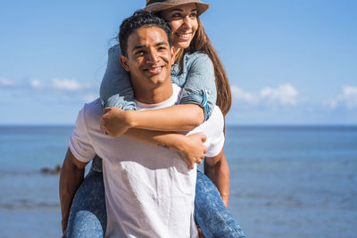 Young man giving piggyback ride to woman at beach
