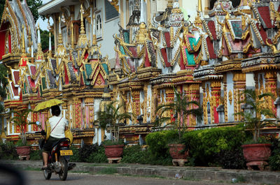 Rear view of man and woman on motorcycle by buddhist temple
