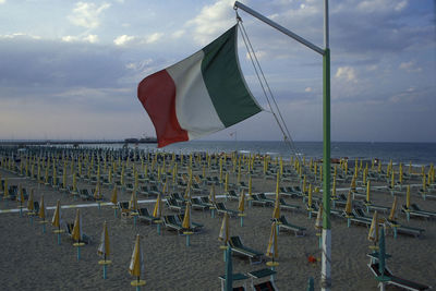 Row of flags on beach against sky