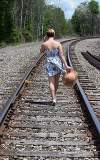 Rear view of young woman walking on railroad track