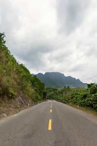 Road leading towards mountains against sky