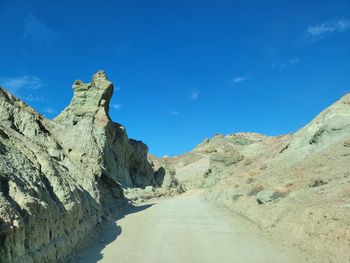 Scenic view of road amidst mountains against blue sky