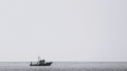 Boat sailing in sea against clear sky