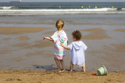 Siblings playing on the beach, the blonde older sister and the dark-haired little brother