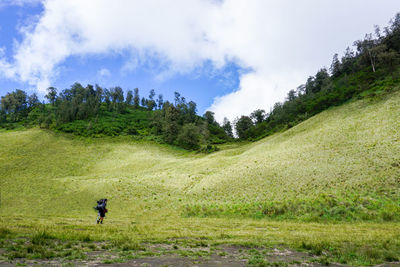Man on green field against sky