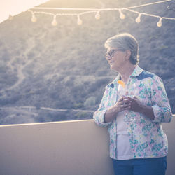 Woman with wine looking away while standing at terrace