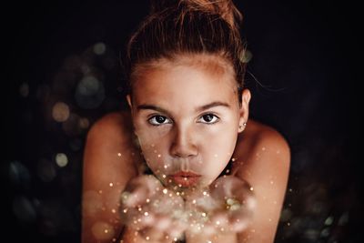 Close-up portrait of girl blowing confetti