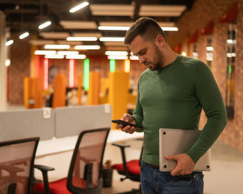 Side view of young man standing in cafe