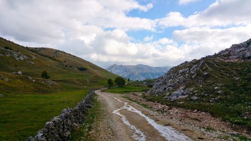 Road leading towards mountains against sky