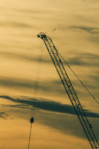 Low angle view of silhouette crane against sky during sunset