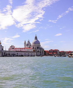 View of buildings at waterfront against cloudy sky