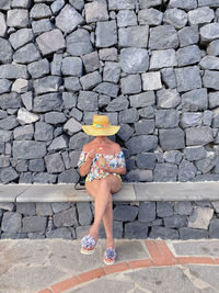 Rear view of a woman standing against stone wall