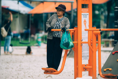 Full length of mature woman playing on outdoor play equipment at playground