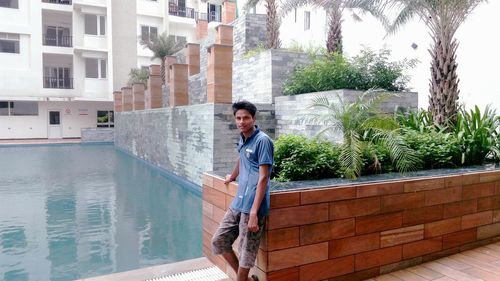 Portrait of young man standing by swimming pool