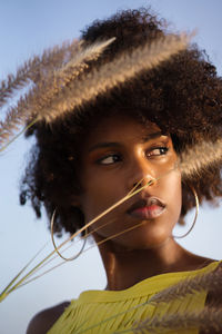 Portrait of a young black woman wearing yellow dress holding grass