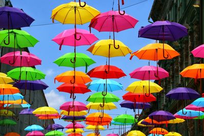 Low angle view of multi colored umbrellas hanging against sky