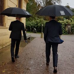 Rear view of people walking on wet street during rainy season