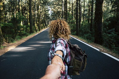 Rear view of woman walking on road in forest