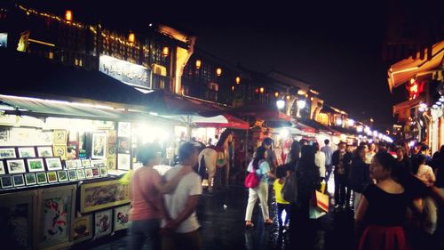 People on footpath in town against sky at night