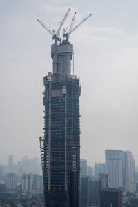 Crane in city against sky