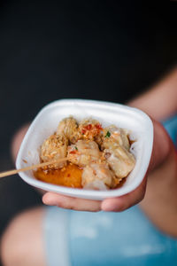 Close-up of hand holding food in bowl