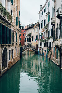 Canal in city against sky