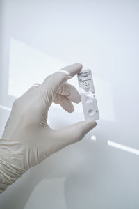 Hand holding rapid diagnostic device with covid-19 positive results against white background
