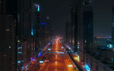 Illuminated street amidst buildings at night