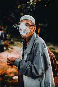 Man exhaling smoke while standing outdoors