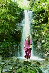 Woman standing by waterfall in forest