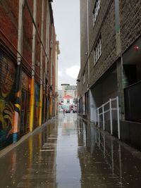 Wet street amidst buildings in city during rainy season