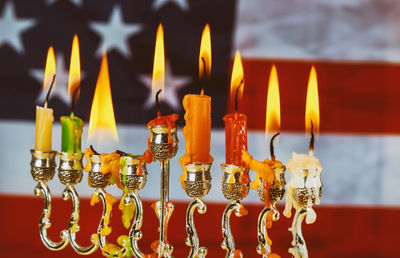 Close-up of illuminated candles on menorah against american flag