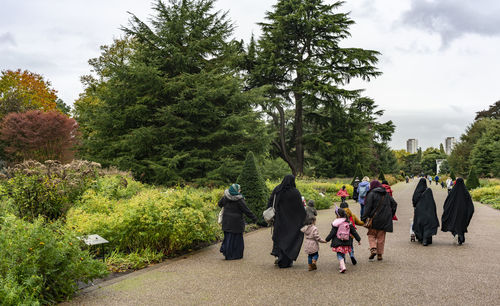 Rear view of people walking along plants
