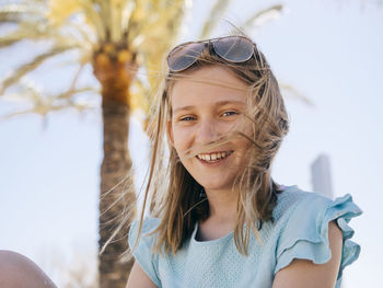 Portrait of smiling girl sitting against sky