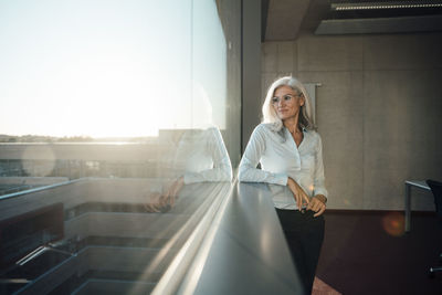 Businesswoman wearing eyeglasses looking through window in office