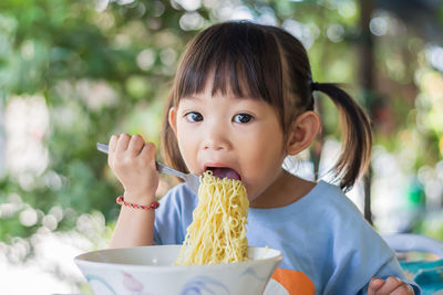 Portrait of cute girl eating noodle at restaurant