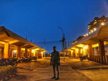 Full length of man standing on illuminated street at night