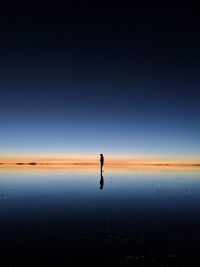 Man standing on beach against clear sky