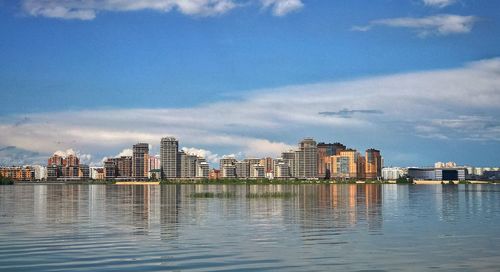 Sea by cityscape against sky