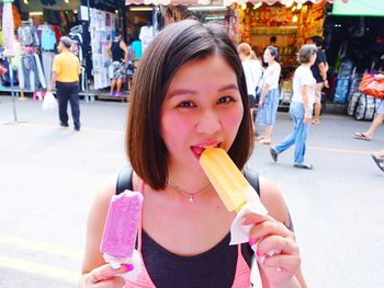 Portrait of woman eating flavored ice on street