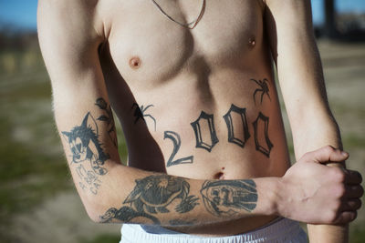 Midsection of shirtless man with tattoo