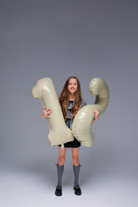 Low angle view of woman with arms raised standing against white background