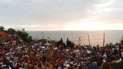 Group of people on beach against sky during sunset