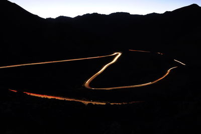 Illuminated silhouette mountain against black background