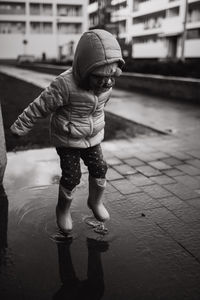 Girl playing in puddle on footpath during rainy season