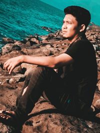 Side view of young man sitting on beach