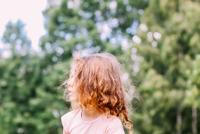 Side view of girl standing against plants