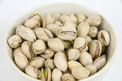 Close-up of pistachio in bowl on white background